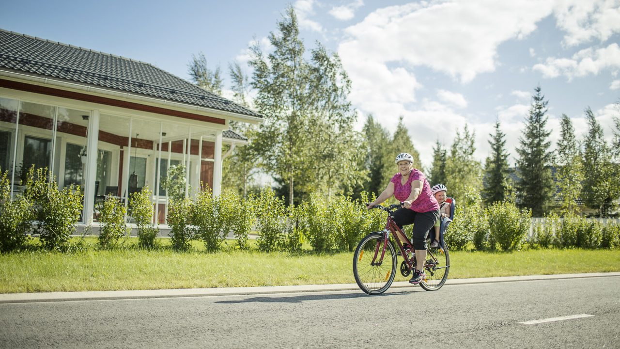 Aikuinen kuljettaa lasta polkupyörällä