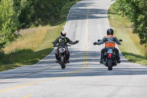 Kaksi motoristia tervehtii toisiaan maantiellä