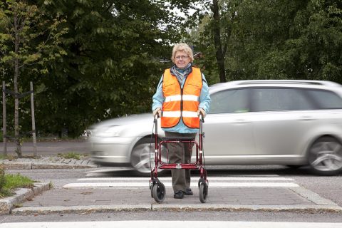 Ikääntynyt jalankulkija suojatiellä rollaattorin kanssa