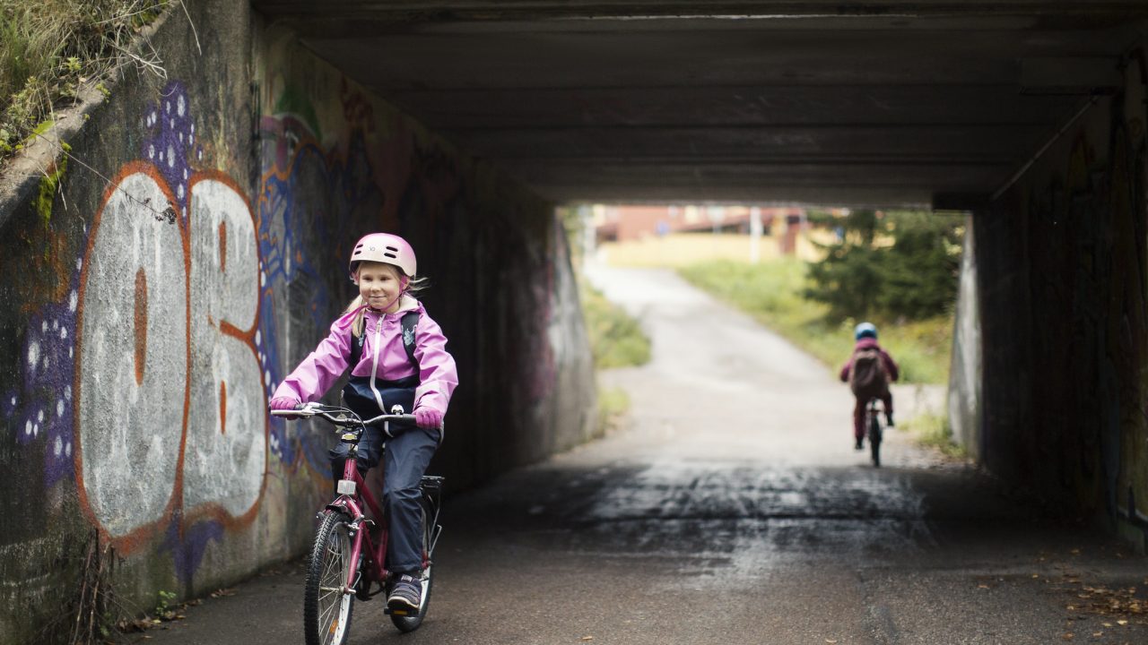 Lapsi pyöräilee alikulkutunnelista ulos.