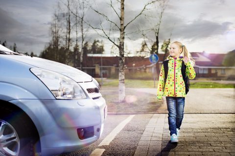 Lapsi ylittää suojatien kuljettajan antaessa tietä.