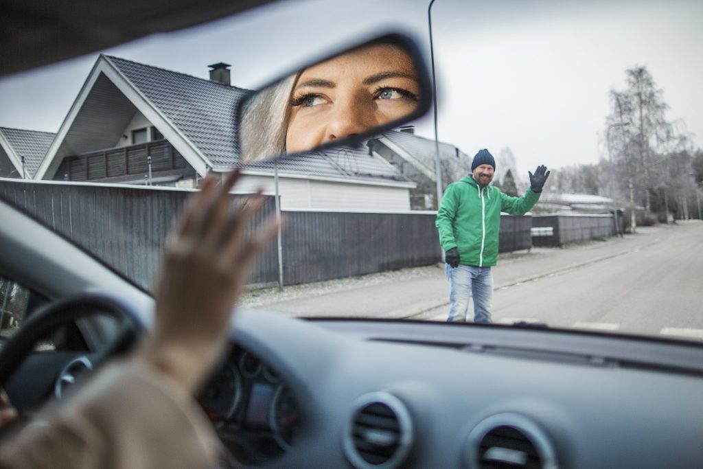 Autoilija antaa jalankulkijalle tietä suojatiellä, ja jalankulkija heilauttaa kättään kiitokseksi.