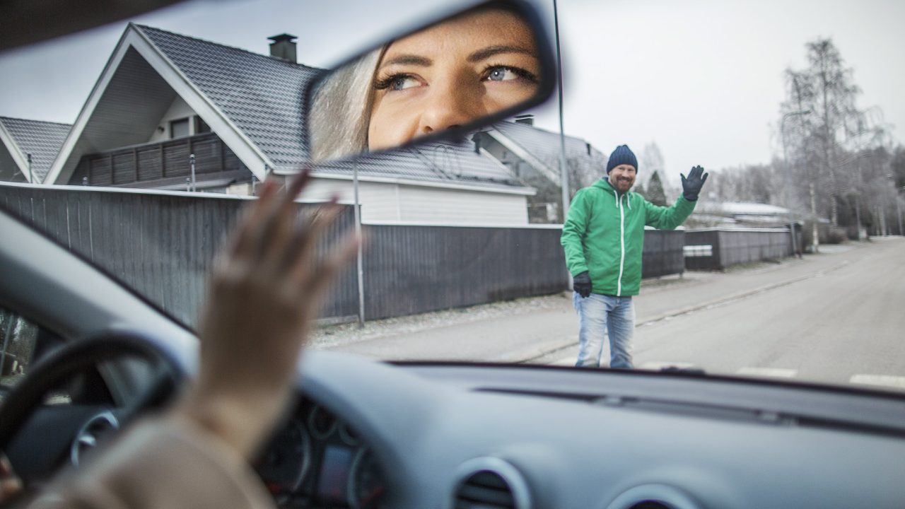 Autoilija antaa jalankulkijalle tietä suojatiellä, ja jalankulkija heilauttaa kättään kiitokseksi.