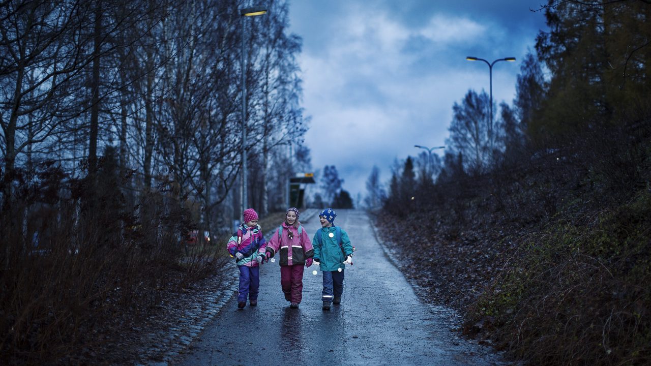 Lapset kävelevät tiellä heijastimet heiluen.