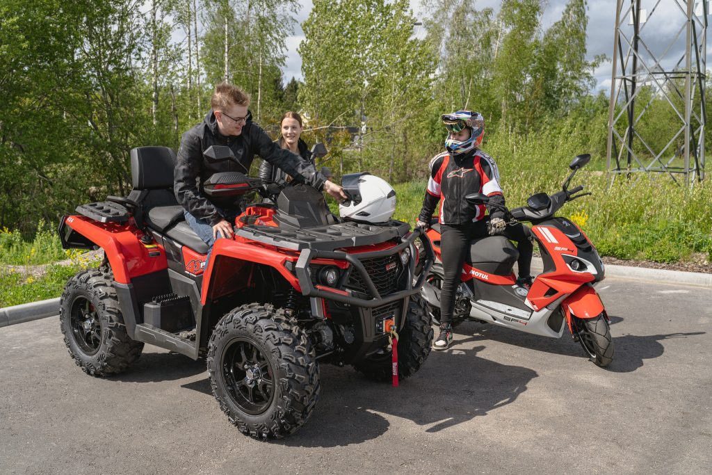 Nuoria parkkipaikalla. Yksi mönkijällä ja kaksi skootterilla. 