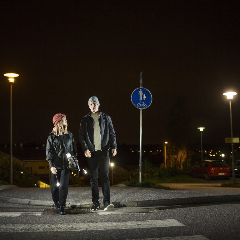 Nuoret ylittämässä suojatietä pimeässä heijastimet heiluen.