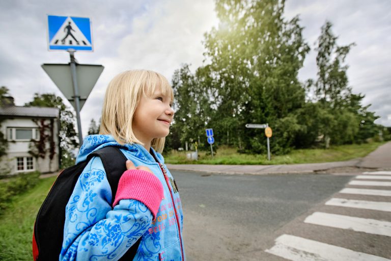 Koululainen pysähtyneenä suojatien eteen.