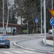 Auto poistuu liikenneympyrästä ja pyöräilijä ylittää tietä