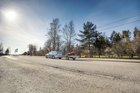 Auto vetää peräkärryä maantiellä.
