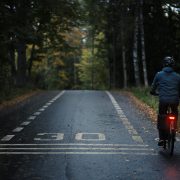 Pyöräilijä polkee hämärässä punainen takavalo loistaen.
