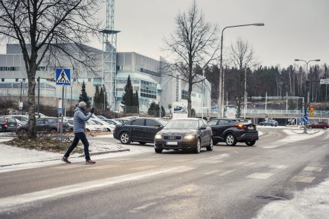 Jalankulkija ylittää suojatien ja heilauttaa autoilijalle kättään kiitokseksi.