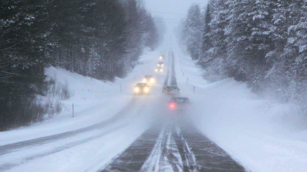 Autoja ajaa talvikelissä maantiellä.