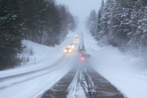 Autoja ajaa talvikelissä maantiellä.