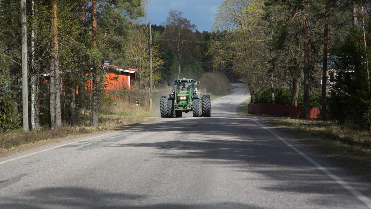 Leveä traktori ajaa maantiellä