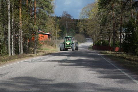 Leveä traktori ajaa maantiellä