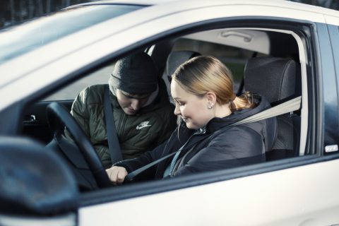 Kuljettaja ja matkustaja kiinnittävät turvavöitä ennen auton käynnistystä.
