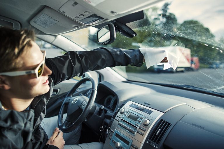 Autoilija puhdistaa tuulilasin myös sisäpuolelta.