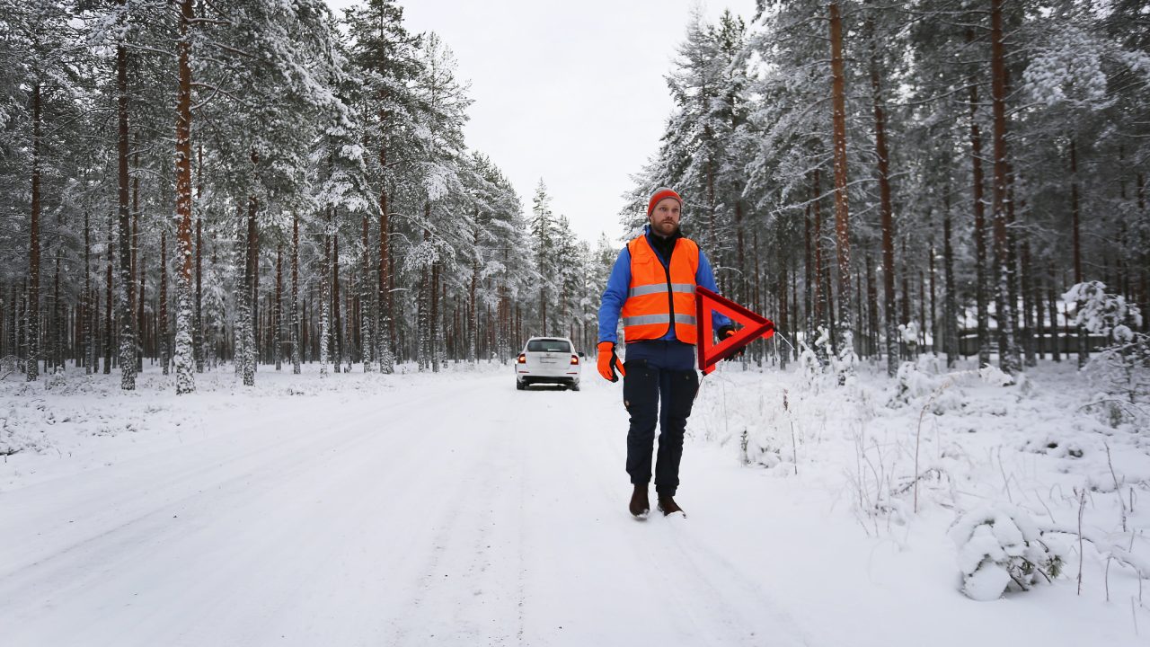 Autoilija vie varoituskolmion varoittamaan muuta liikennettä.