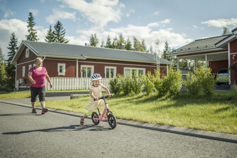 Lapsi potkupyöräilee isovanhemman kanssa.