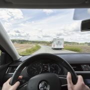 Henkilöautoilija ohittaa matkailuautoa maantiellä.