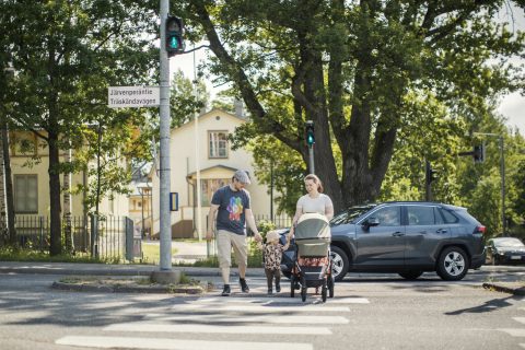 Perhe ylittää tien suojatietä pitkin.