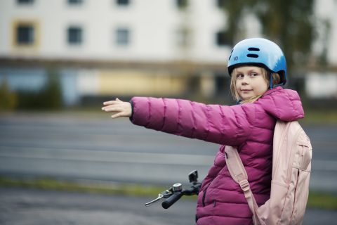 Pyöräilevä lapsi näyttää suuntamerkkiä.