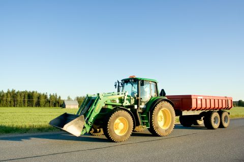 Kuvassa traktori ajaa pellon viereistä tietä.