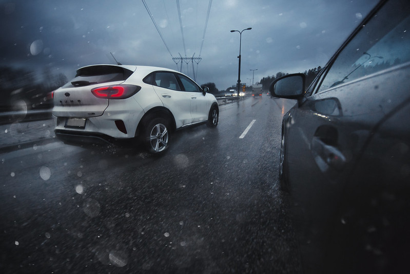 Kaksi autoa ajaa rinnakkain sateisella ja hämärällä kelillä