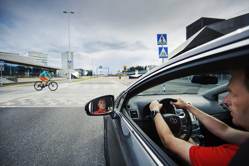 Autoilija antaa tietä pyöräilijälle pyöräilijän tienylityspaikassa.