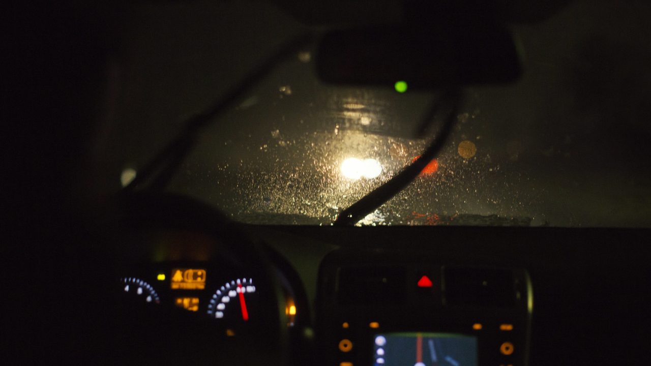 Sateinen ja pimeä ajokeli ratin takaa katsottuna.