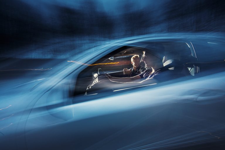 Autossa kuljettaja ja matkustajia.