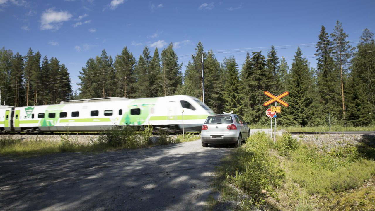 auto pysähtyneenä tasoristeykseen. Juna menee ohi