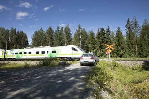 auto pysähtyneenä tasoristeykseen. Juna menee ohi