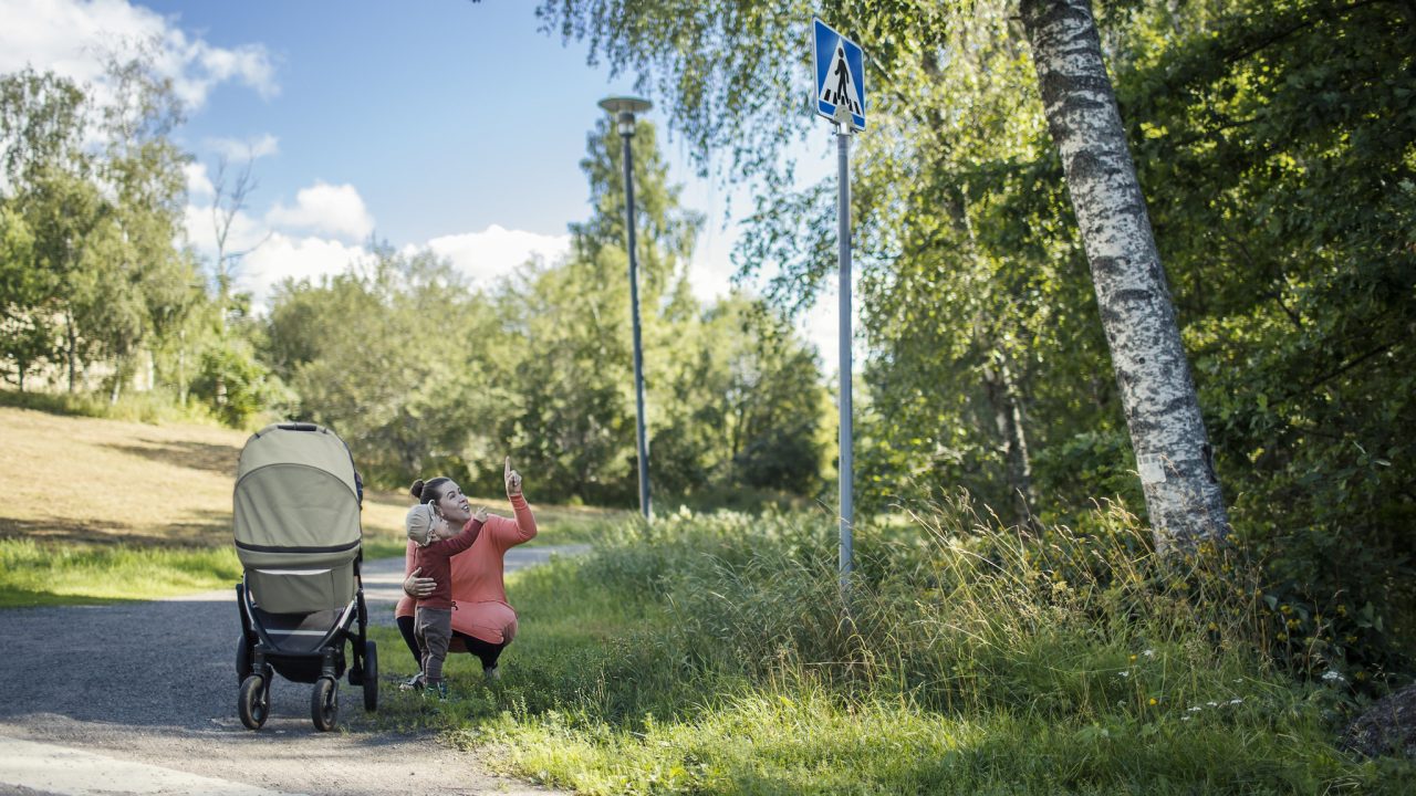 Vanhempi opettaa lasta liikenteessä.