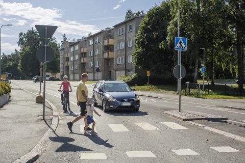 Autoilija ja pyöräilijä antavat tietä suojatietä ylittäville jalankulkijoille.