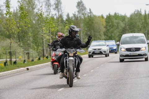 Mopoilija kiittää autoilijaa, joka antaa hänelle tietä.