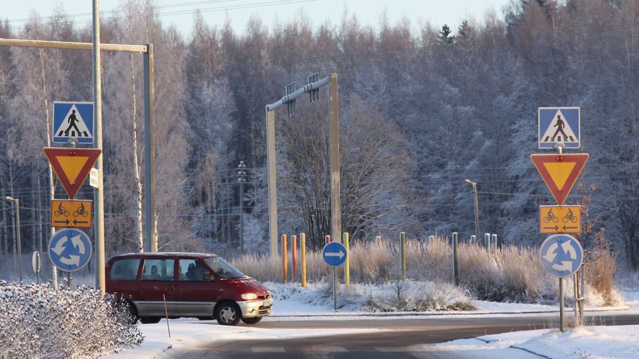 Punainen pakettiauto ajaa liikenneympyrässä