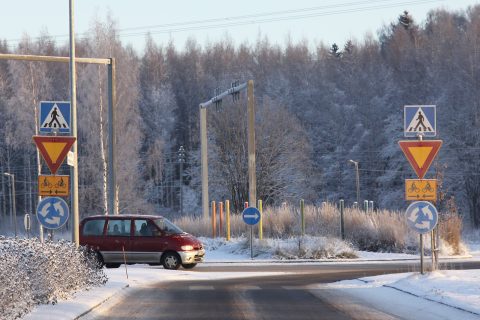 Punainen pakettiauto ajaa liikenneympyrässä