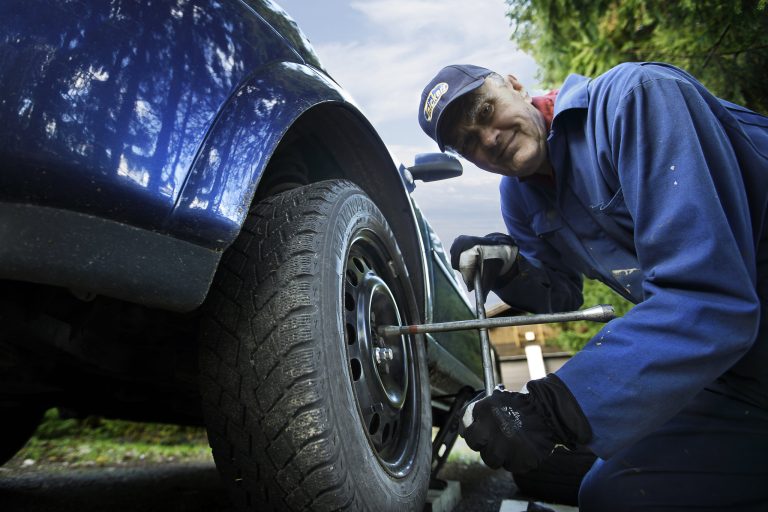 Autokorjaaja kiristämässä autonrenkaiden pultteja.