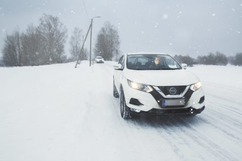 Auto lumisella tiellä toinen auto seuraa.