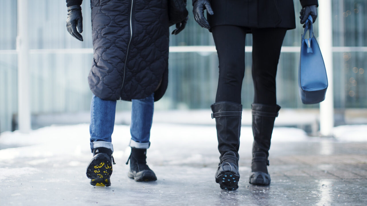 Jalankulkijat kävelevät kohti liukkaalla alustalla nastakengät jaloissaan.