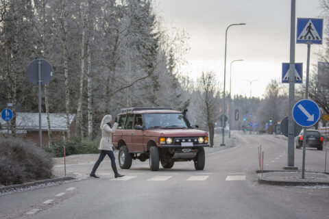 Autoilija antaa tietä suojatietä ylittävälle kävelijälle. Kävelijä tervehtii autoilijaa.