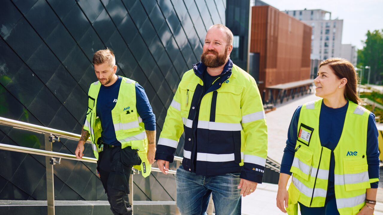 Kolme Aren työntekijää kävelemässä portaita ylös.