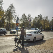 auto ja pyöräilijä pysähtyneenä punaisiin liikennevaloihin risteyksessä.
