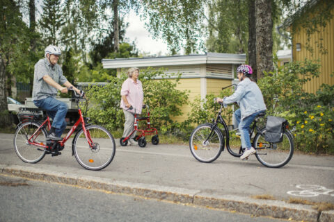 Kaksi pyöräilijää ja apuvälinettä käyttävä henkilö kohtaavat tiellä.