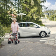 Ikääntynyt suojatien ylittäjä rollaattorin kanssa.