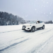 Auto ajaa lumisella tiellä.