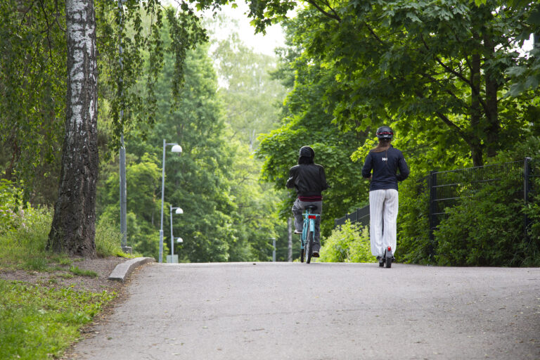Pyöräilijä ja sähköpotkulautailija ajavat samaan suuntaan.