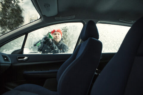 Autoilija skrapaa ikkunaa jäästä.