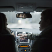 Etupenkin matkustaja osoittaa kojetaulua kuljettajalle.